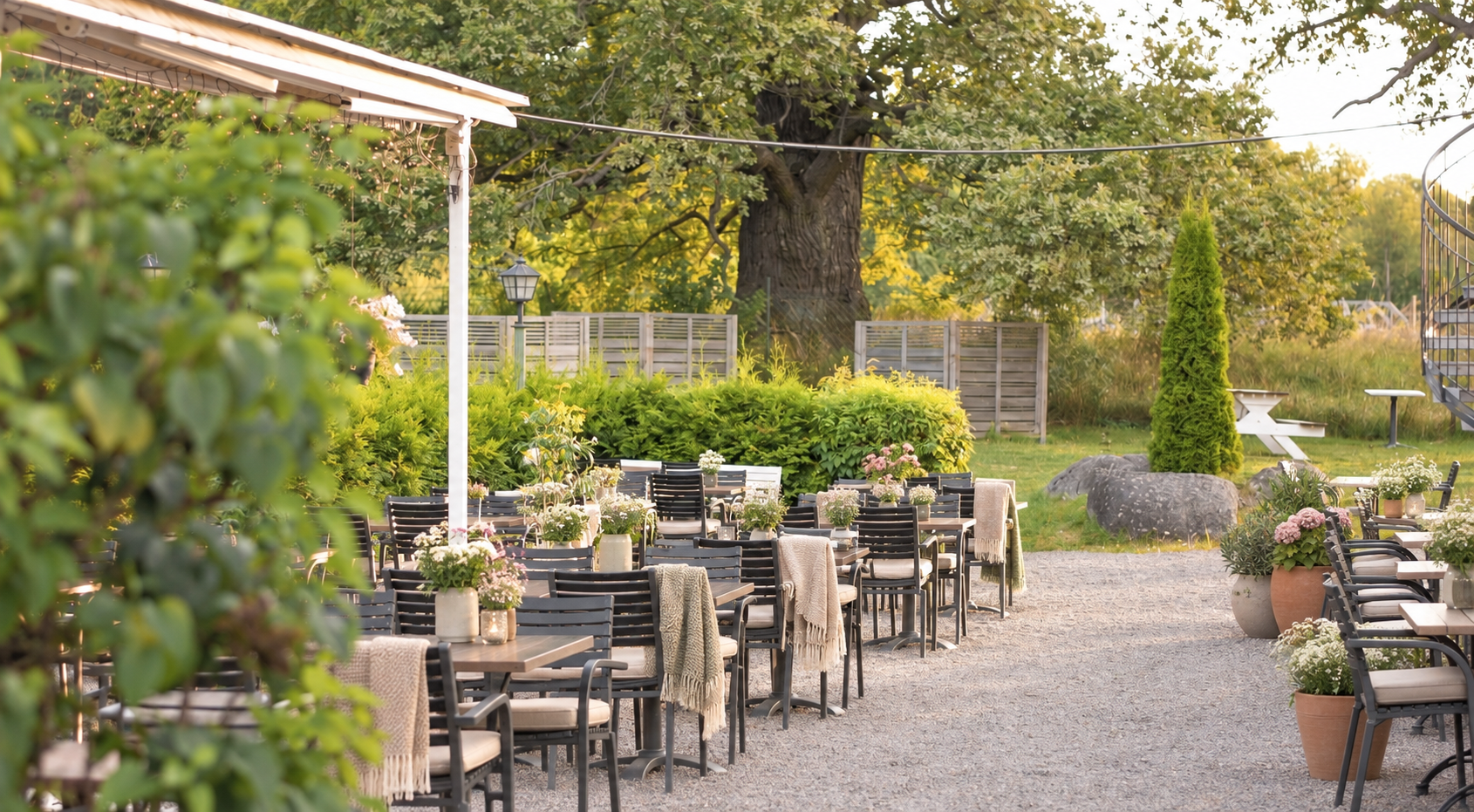 Brostugans uteplats med dynor, filtar och sommarblommor